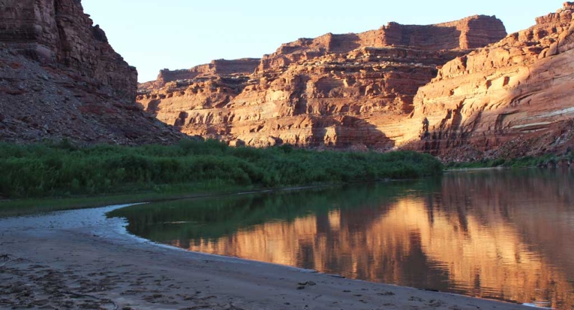 A calm river flows between high, red rock walls.